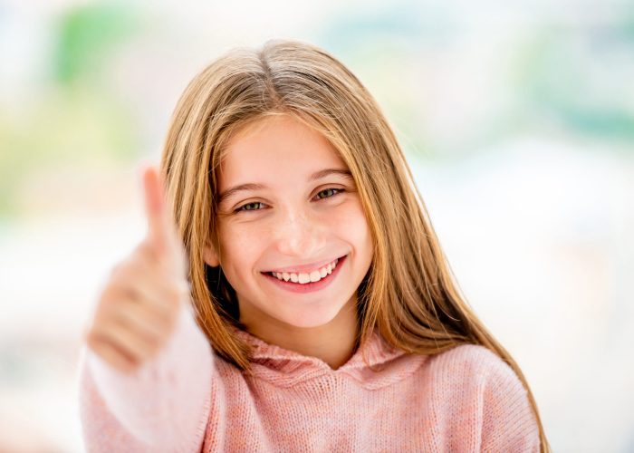 Happy school girl showing thumb up